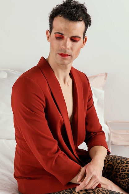 Photo gratuite personne transgenre portant une veste rouge et assise sur le lit