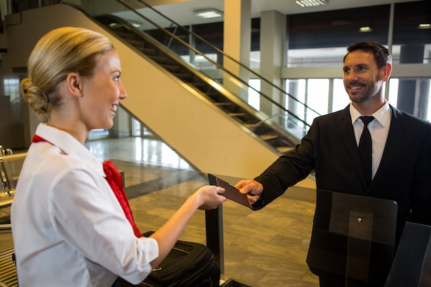 Personnel féminin donnant la carte d'embarquement au passager