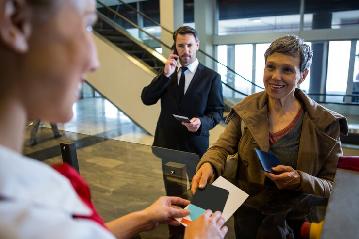 Photo gratuit personnel féminin donnant la carte d'embarquement au passager