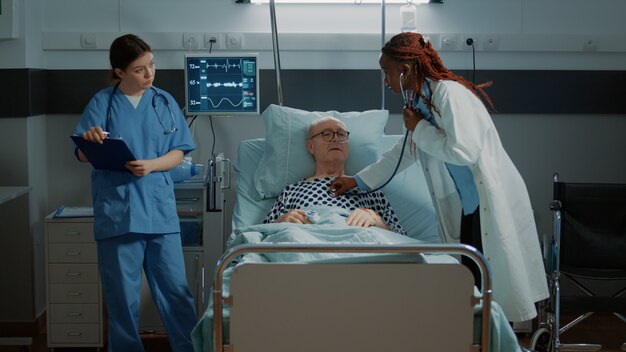 Le personnel multiethnique traite le patient dans la salle d'hôpital