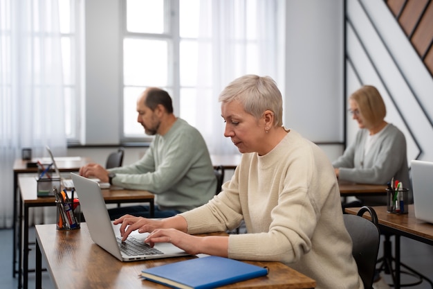 Personnes âgées à l'école pendant les cours avec un ordinateur portable