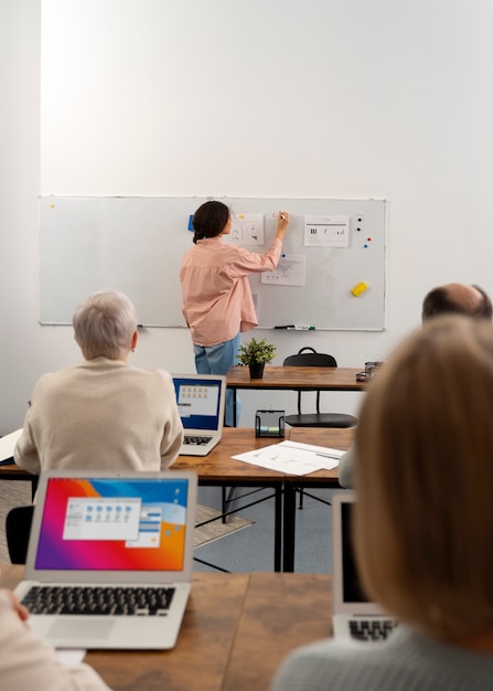 Photo gratuite personnes âgées à l'école pendant les cours avec un ordinateur portable