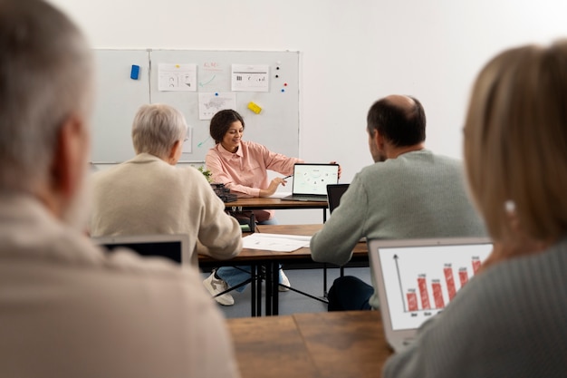 Photo gratuite personnes âgées à l'école pendant les cours avec un ordinateur portable