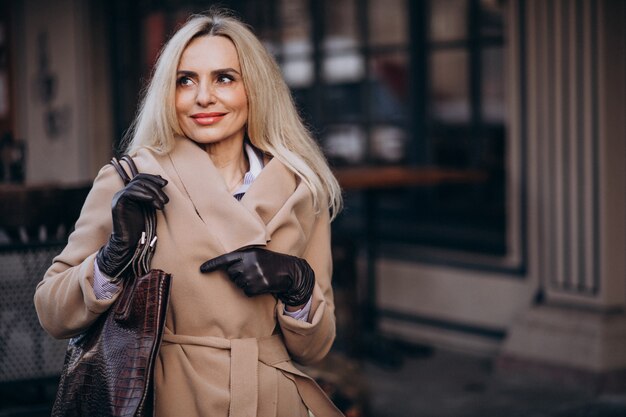 Personnes âgées femme d'affaires dans un manteau avec des gants dans la rue