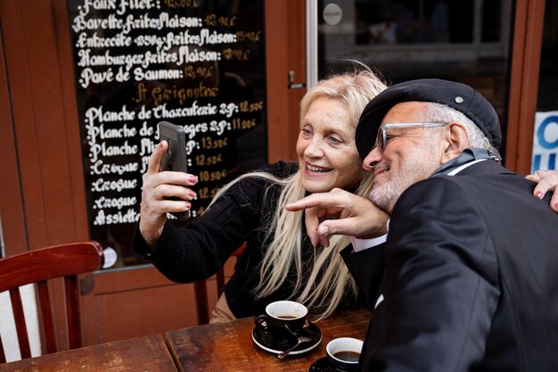 Personnes âgées souriantes à coup moyen prenant selfie