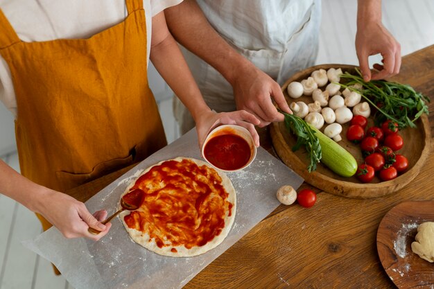 Personnes à angle élevé cuisinant des pizzas ensemble