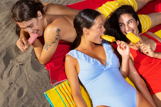 Personnes à angle élevé mangeant des glaces sur la plage