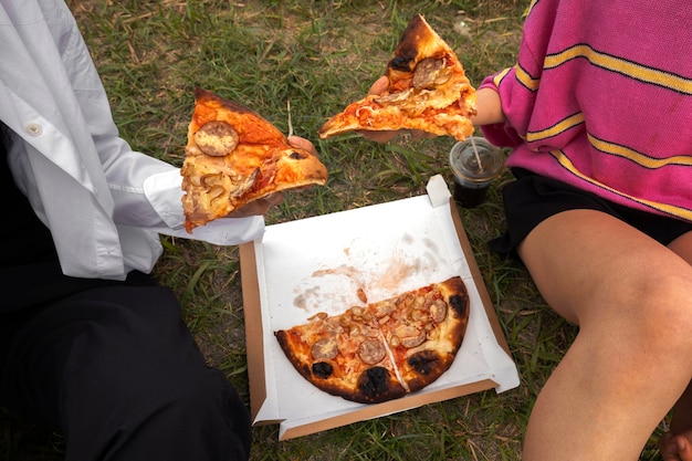 Personnes appréciant la pizza ensemble à l'extérieur
