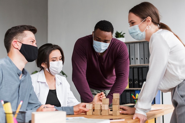 Personnes ayant une réunion au bureau pendant la pandémie avec des masques sur