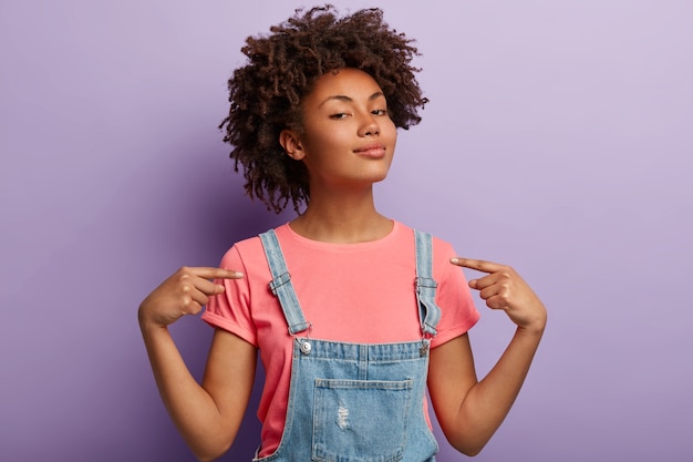 Personnes, fierté, concept d'arrogance. Une femme fière et sûre d'elle-même a une coiffure afro satisfaite de ses propres réalisations, se sent confiante