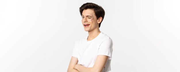 Personnes lgbtq et concept de beauté bel homme gay effronté faisant un clin d'œil à la caméra et souriant debout avec