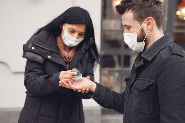 Les personnes portant un masque de protection debout dans la rue tout en utilisant du gel d'alcool