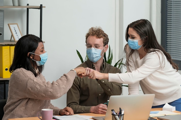 Personnes portant des masques médicaux travaillant ensemble pour un projet