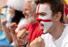 Photo gratuite personnes regardant ensemble un match de football par une journée ensoleillée