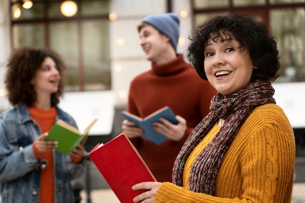 Photo gratuite personnes souriantes à coup moyen tenant des livres