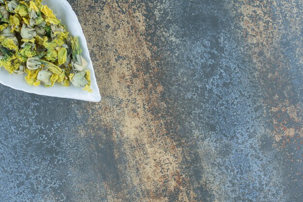 Pétales de chrysanthème séchés sur plaque en forme de feuille.