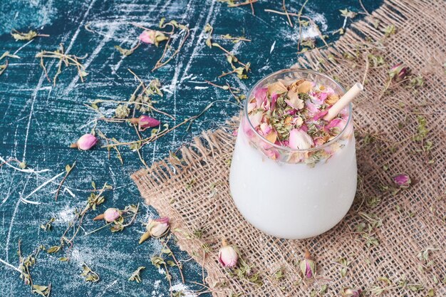 Pétales et crème avec une tasse de boisson sur bleu.