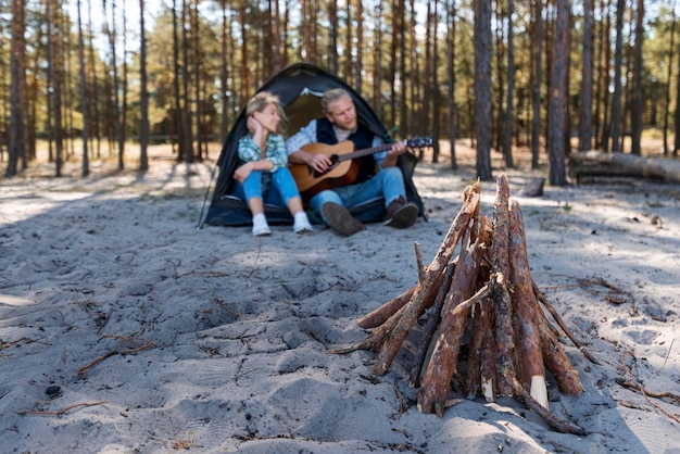 Photo gratuite petit ami jouant de la guitare acoustique et du bois de feu de camp