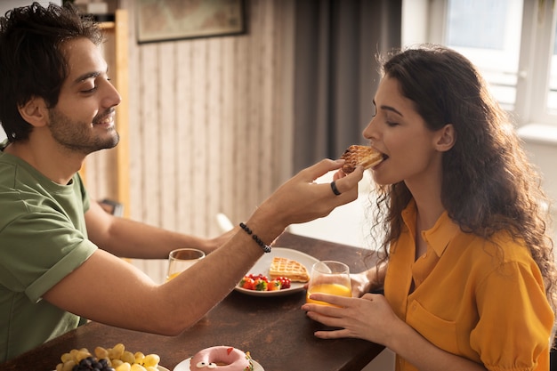 Photo gratuite petit ami et petite amie mangeant des gaufres ensemble à la maison