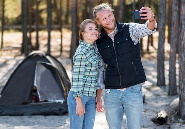 Petit ami prenant un selfie avec leur tente à l'arrière