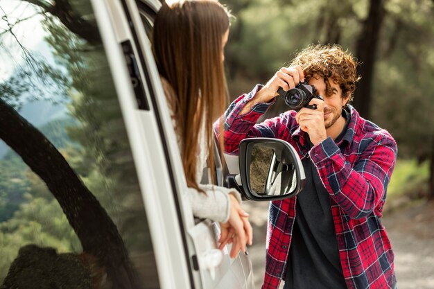 Petit ami à prendre des photos de petite amie dans la voiture lors d'un voyage sur la route