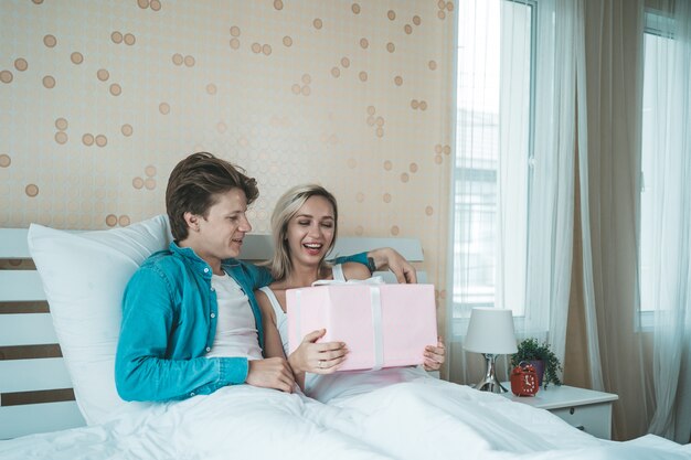 Petit ami surprend sa copine avec une boîte cadeau sur le lit