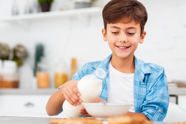 Petit angle garçon préparant des céréales avec du lait