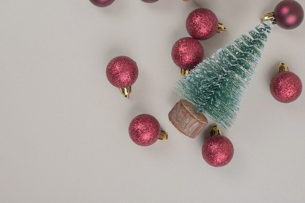 Petit arbre de Noël avec des boules de Noël rouges sur une surface blanche