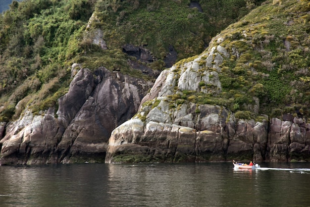 Petit bateau dans le lac entouré de montagnes herbeuses vertes