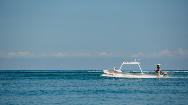 Petit bateau flotte sur l'eau avec des montagnes.