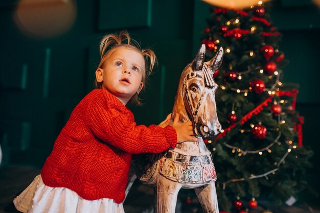 Petit bébé gir; l par sapin de Noël avec jouet en bois