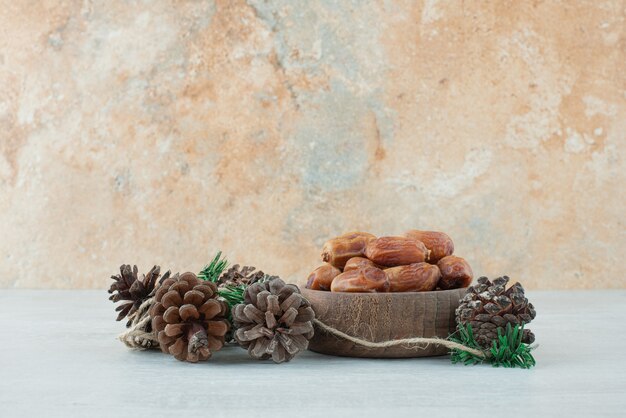 Un petit bol en bois de fruits secs et de pommes de pin sur fond de marbre. Photo de haute qualité