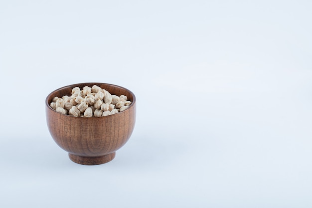 Un petit bol en bois plein de pois blancs crus.