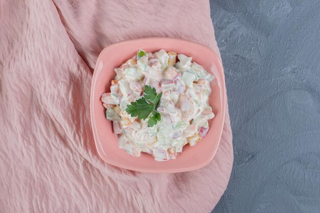 Petit bol de salade d'olivier garni de feuilles de persil sur nappe rose sur fond de marbre. ''