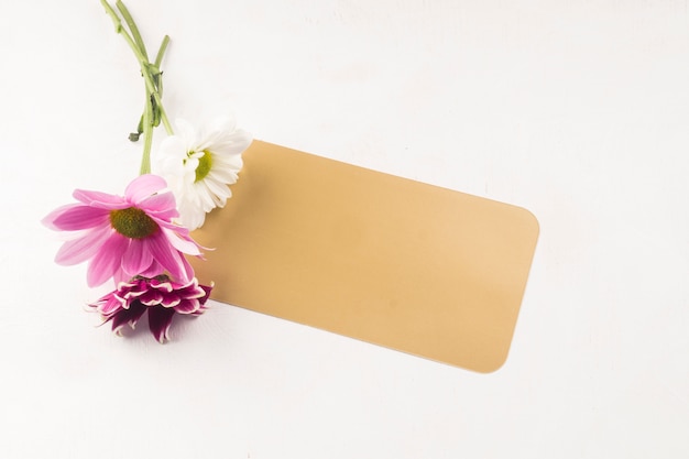 Petit bouquet avec carte-cadeau posée sur un bureau blanc