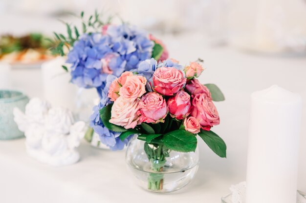 Petit bouquet de roses roses placé dans un vase en verre