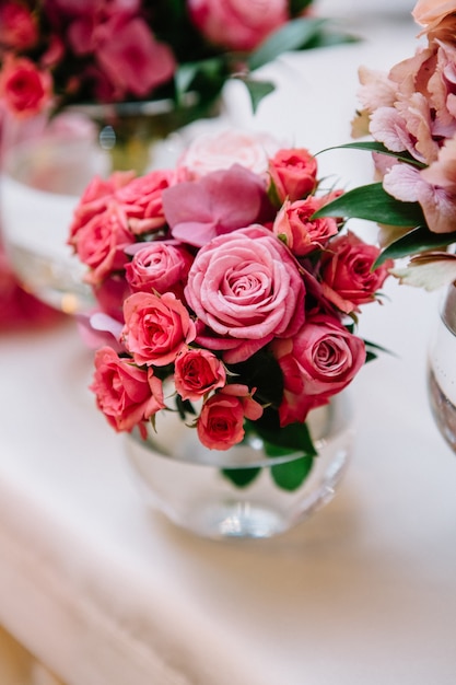 Petit bouquet de roses roses placé dans un vase en verre