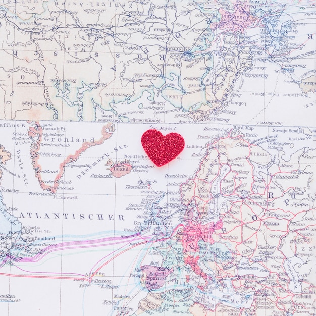 Petit coeur de papier rouge sur la carte du monde