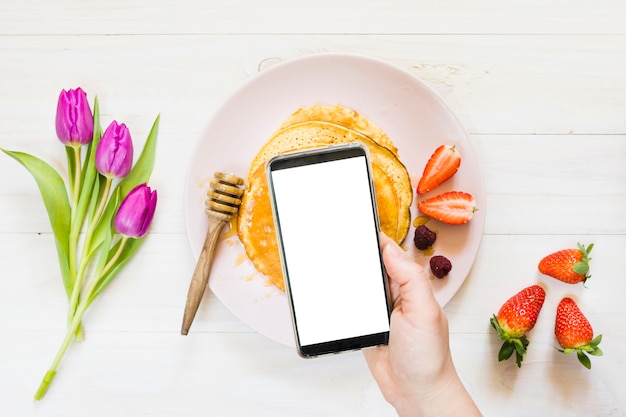 Photo gratuite petit déjeuner aux crêpes avec téléphone portable