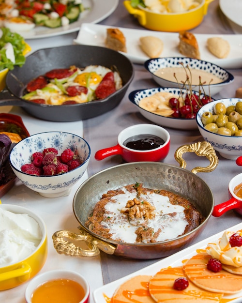 Petit déjeuner azerbaïdjanais traditionnel appétissant avec kookoo, saucisse et œuf, pancake, salade