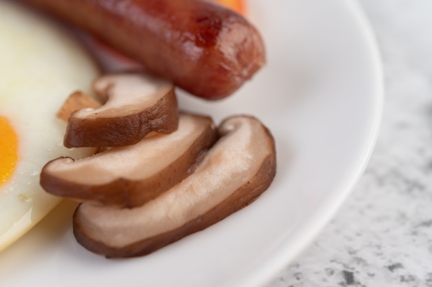 Petit déjeuner composé de pain, œufs au plat, tomates, saucisse chinoise et champignons.