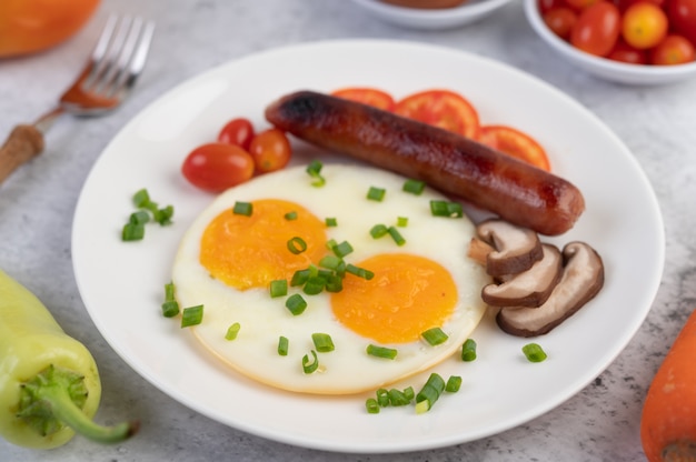 Petit déjeuner composé de pain, œufs au plat, tomates, saucisse chinoise et champignons.