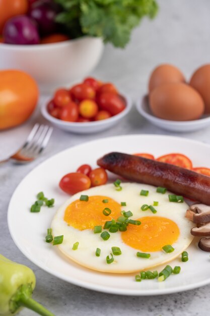 Petit déjeuner composé de pain, œufs au plat, tomates, saucisse chinoise et champignons.