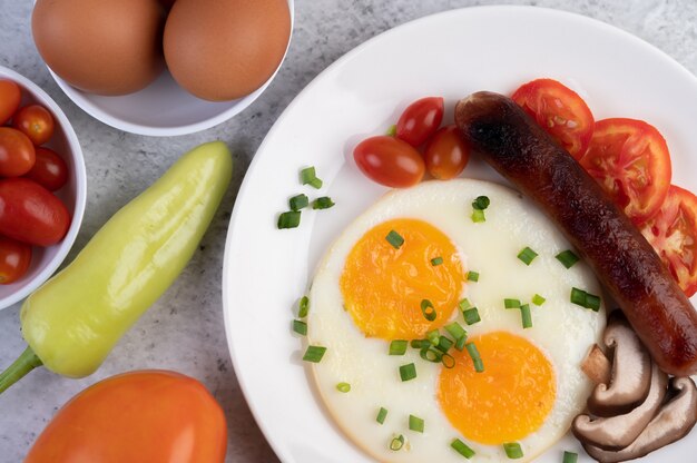 Petit déjeuner composé de pain, œufs au plat, tomates, saucisse chinoise et champignons.