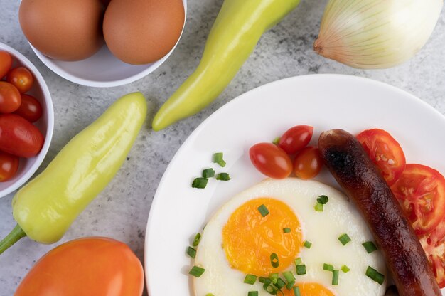 Petit déjeuner composé de pain, œufs au plat, tomates, saucisse chinoise et champignons.