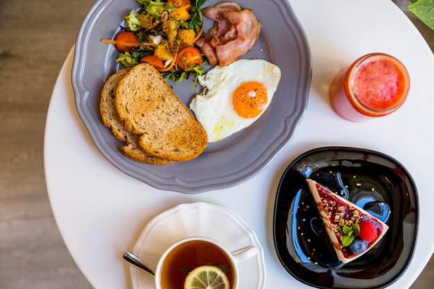 Petit déjeuner avec dessert; smoothie et thé sur une table ronde blanche