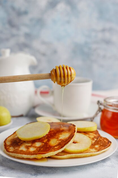 Petit déjeuner maison: pancakes de style américain servis avec des poires et du miel avec une tasse de thé sur du béton. Vue de dessus et copie