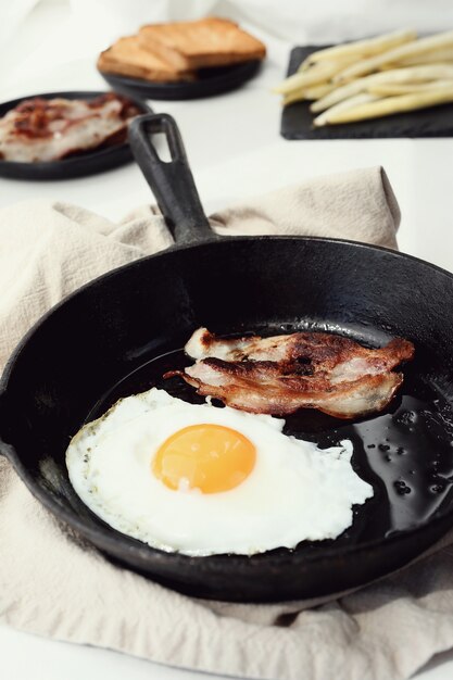 Petit déjeuner d'œufs et de bacon frit dans la poêle