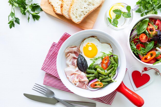 Petit-déjeuner pour votre bien-aimé pour les vacances œuf en forme de coeur haricots verts sur un tableau blanc Mise au point sélective Vue de dessus Copier l'espace