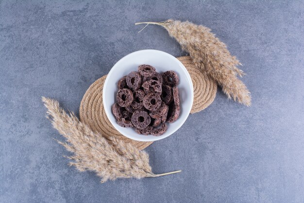 Petit-déjeuner sain avec des anneaux de maïs au chocolat dans une assiette sur pierre.